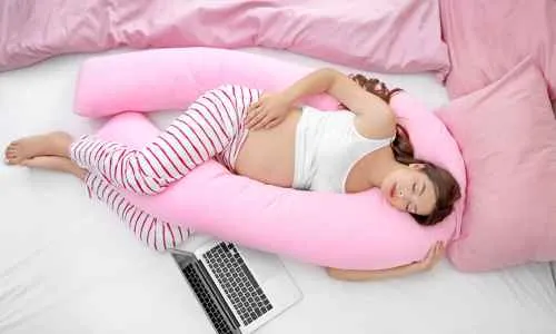 a pregnant person sleeping on a pink pillow
