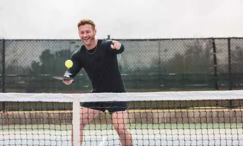 a person holding a pickleball paddle and a ball and switching hands in pickleball
