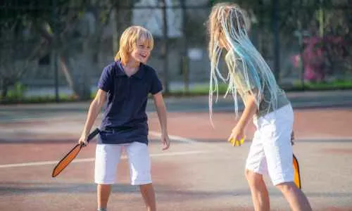 a child and child playing pickleball on the court