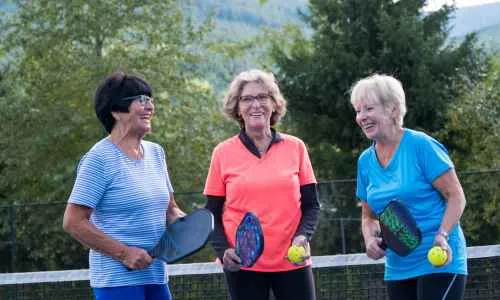 a group of women holding paddles and pickleballs
